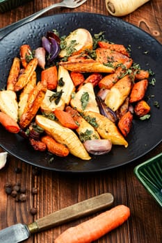 Healthy homemade roasted parsnip root, carrots and garlic with herbs.