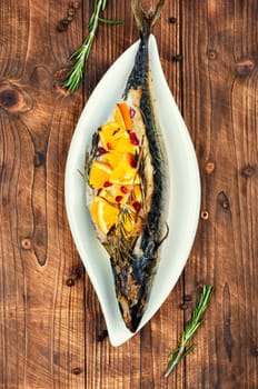 Mackerel fish baked with oranges and rosemary on old rustic wooden table.