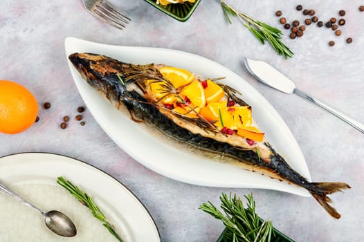 Mackerel fish baked with oranges and rosemary on old rustic wooden table.