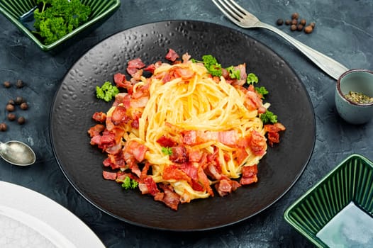 Pasta or spaghetti carbonara with bacon and parmesan on a plate. Close up.