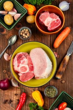 Juicy raw piece meat and vegetables on rustic wooden table. Set of ingredients for soup or borscht.