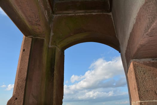 View through an old castle window on a blue sky with white clouds