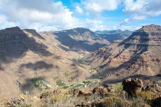 Mountains with a small village in the valley on the Canary Island of Gran Canaria in Spain, with blue sky and clouds