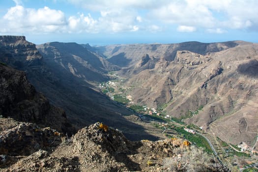 Mountains with a small village in the valley on the Canary Island of Gran Canaria in Spain, with blue sky and clouds