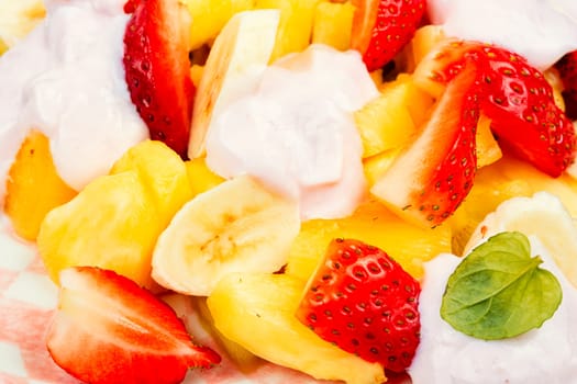 Summer fruit salad of pineapple, strawberries, kiwi and yogurt on a plate.