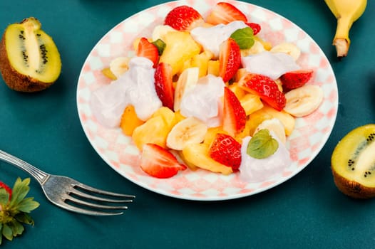 Summer fruit salad of pineapple, strawberries, kiwi and yogurt on a plate.