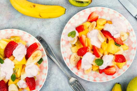 Summer fruit salad of pineapple, strawberries, kiwi and yogurt on a plate.