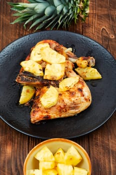 Chicken legs fried with pineapple pieces. Grilled chicken, grilled chicken legs on old wooden table.
