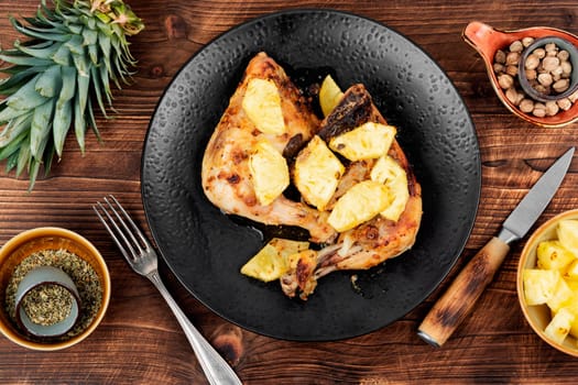 Chicken legs fried with pineapple pieces. Grilled chicken, grilled chicken legs on old wooden table.
