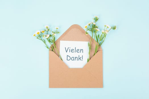 Thank you card, german language, envelope surrounded by spring flowers, being thankful, support, help and charity concept, positive attitude