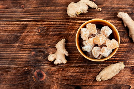 Dried candied ginger pieces and fresh rhizome root, candied ginger dessert.