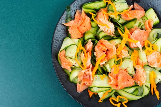 Fresh spring salad with smoked salmon, cucumber on a concrete kitchen table. Asian cuisine.