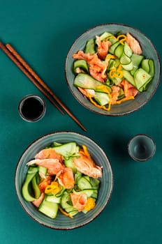 Fresh spring salad with smoked salmon, cucumber on a concrete kitchen table. Asian cuisine.
