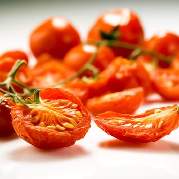 Close-up of sun-dried cherry tomatoes with a vibrant red color and visible seeds, on a white surface.
