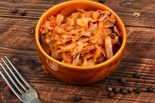 Appetizing stewed cabbage on the old wooden background. German cuisine. Rustic style.