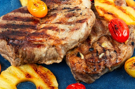 Tasty grilled meat,roasted with pineapple on stone background. Grilled steak and ananas. Top view.