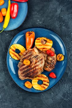 Tasty grilled meat,roasted with pineapple on stone background. Grilled steak and ananas. Top view.