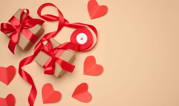 Gift box with red satin ribbon and bow on a beige background. Holiday background, copy space