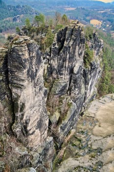 Jagged rocks at the Basteibridge. Wide view over trees and mountains. National park in Germany
