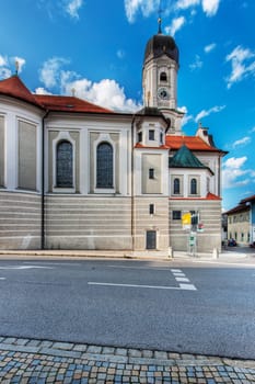 South facade of the Saint Andreas Church in Nesselwang Bavaria from the south across the main street in front of a blue sky with clouds in summer 2023.