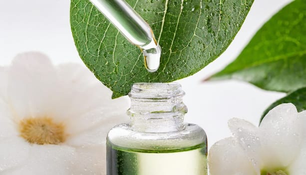 Herbal essence. Alternative healthy medicine. Skin care. Essential oil or water dropping from fresh leaf to the bottle.