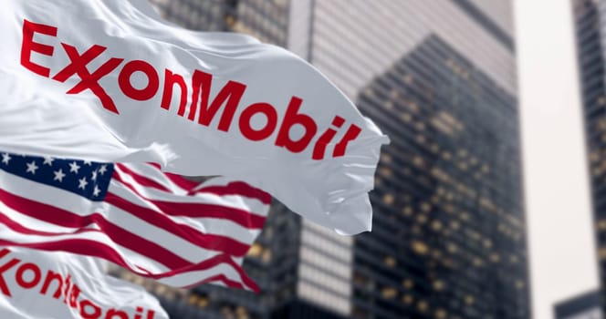 Spring, US, Oct. 5 2023: ExxonMobil and the American flags waving in the wind in a financial district. American multinational oil and gas corporation. Illustrative editorial 3d illustration render