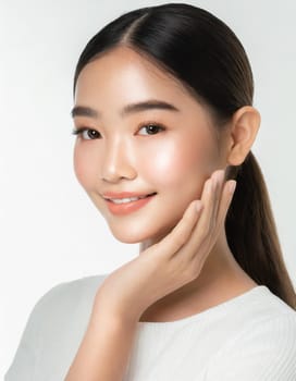Skin care. Woman with beauty face touching healthy facial skin portrait. Beautiful smiling asian girl model with natural makeup touching glowing hydrated skin on blue background closeup