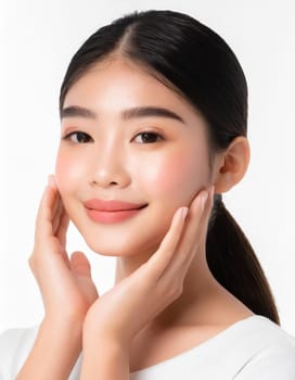 Skin care. Woman with beauty face touching healthy facial skin portrait. Beautiful smiling asian girl model with natural makeup touching glowing hydrated skin on blue background closeup