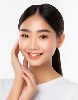 Skin care. Woman with beauty face touching healthy facial skin portrait. Beautiful smiling asian girl model with natural makeup touching glowing hydrated skin on blue background closeup