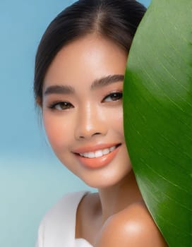 Gorgeous Asian young woman with a fresh leaf to her face