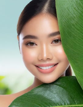 Gorgeous Asian young woman with a fresh leaf to her face