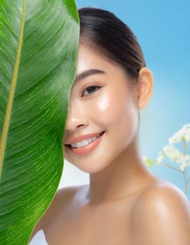 Portrait of young beautiful woman with healthy glow perfect smooth skin holds green tropical leaf, look into the hole of colored pink paper. Model with natural nude make up. Fashion, beauty, skincare