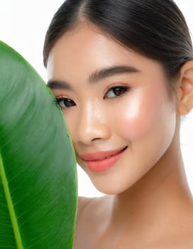Gorgeous Asian young woman with a fresh leaf to her face
