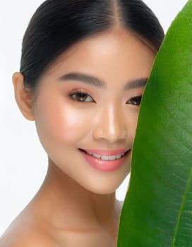 Gorgeous Asian young woman with a fresh leaf to her face