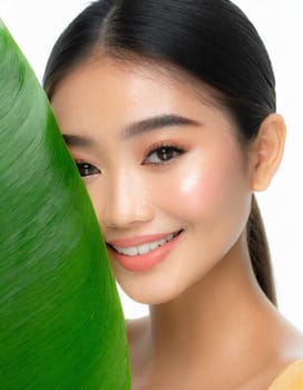 Gorgeous Asian young woman with a fresh leaf to her face