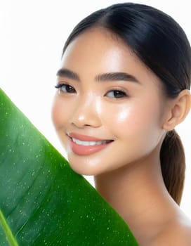 Gorgeous Asian young woman with a fresh leaf to her face