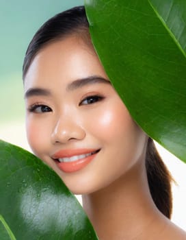 Gorgeous Asian young woman with a fresh leaf to her face