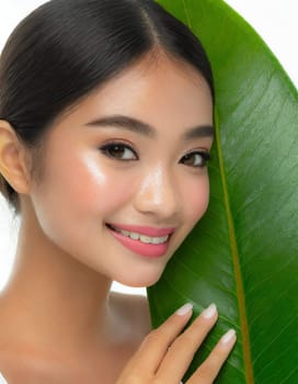 Gorgeous Asian young woman with a fresh leaf to her face