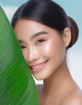 Gorgeous Asian young woman with a fresh leaf to her face