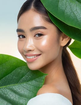 Gorgeous Asian young woman with a fresh leaf to her face