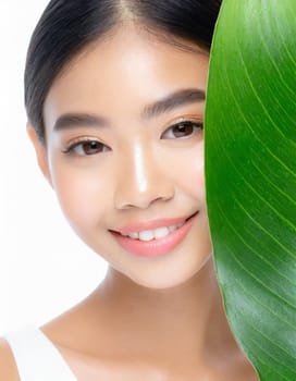 Gorgeous Asian young woman with a fresh leaf to her face