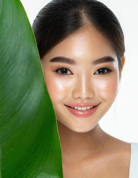 Gorgeous Asian young woman with a fresh leaf to her face