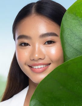 Gorgeous Asian young woman with a fresh leaf to her face