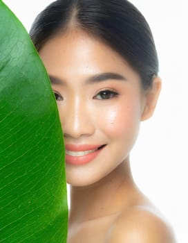 Gorgeous Asian young woman with a fresh leaf to her face