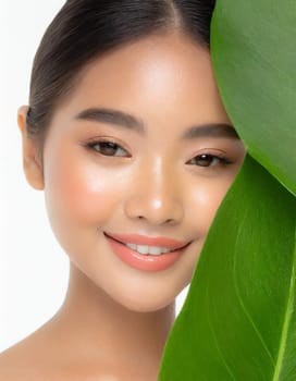 Gorgeous Asian young woman with a fresh leaf to her face