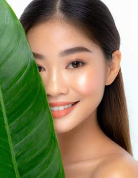 Gorgeous Asian young woman with a fresh leaf to her face