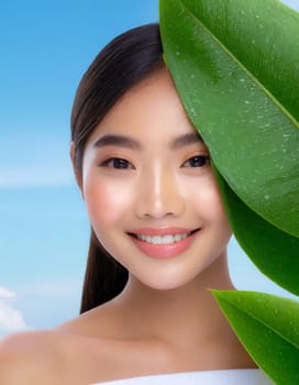 Gorgeous Asian young woman with a fresh leaf to her face