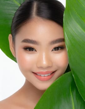 Gorgeous Asian young woman with a fresh leaf to her face