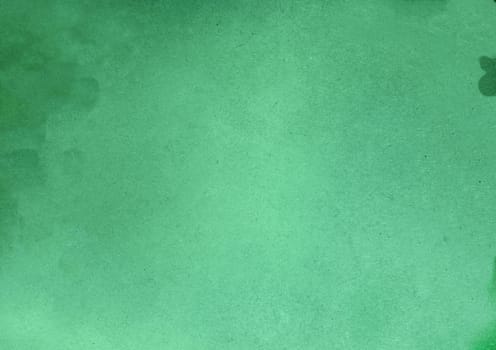 Background texture of a rough surface with villi, spots and particles on a green background close-up view from above