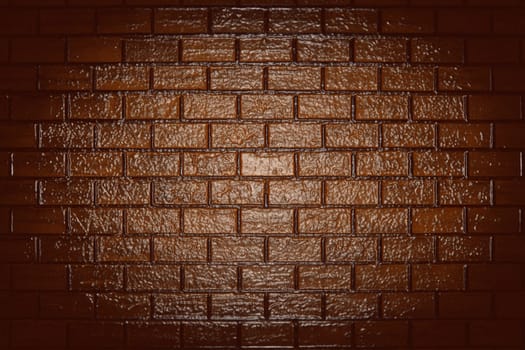 A rough glossy brown brick wall with a backlight in the center and shadow around the edges. Texture or background
